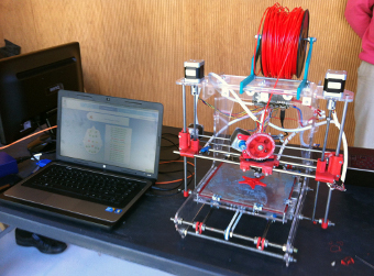Impresora 3D junto a equipo con software para impresión